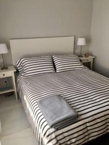 ein Schlafzimmer mit einem großen Bett mit gestreifter Bettwäsche und Kissen in der Unterkunft Maravilla del Castro in Vigo