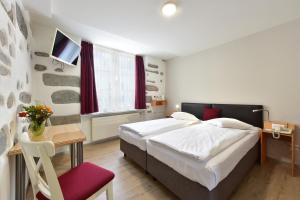 a bedroom with a bed and a table and a tv at Hotel Hirschen in Zürich
