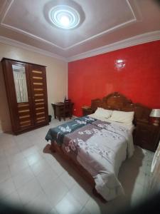 a bedroom with a bed with a red wall at SAM RESIDENCE Jàmm ak Cofeel in Saint-Louis