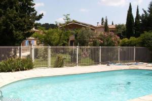 une clôture autour d'une piscine en face d'une maison dans l'établissement Au coeur des Alpilles Rdc Jardin et Piscine, à Paradou