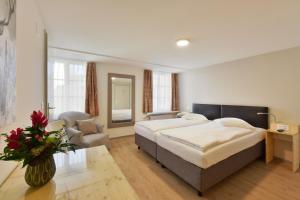 a bedroom with a large bed and a chair at Hotel Hirschen in Zürich
