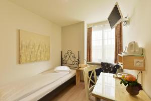 a small room with a bed and a desk and a window at Hotel Hirschen in Zürich