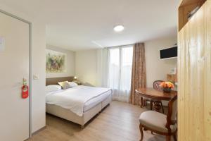 a bedroom with a bed and a table and a window at Hotel Hirschen in Zürich