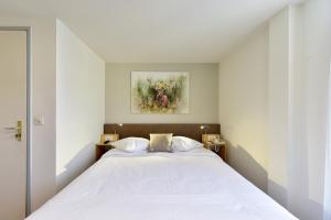 a bedroom with a white bed with a painting on the wall at Hotel Hirschen in Zürich