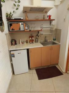 una pequeña cocina con fregadero y nevera. en Spring apartment Bahar nissim Jerusalem, en Jerusalén