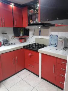een keuken met rode kasten en een fornuis met oven bij Residencial Las Torres de Salaverry in Chiclayo