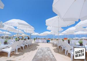 a beach with white chairs and tables and umbrellas at Tel-Aviv center, near the beach, terrace, 4 people in Tel Aviv