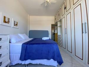 een slaapkamer met een blauw bed en witte kasten bij Apto a beira mar no Centro - WIFI 200MB - TV Smart - Cozinha equipada - Portaria 24h - Ar condicionado in Rio das Ostras