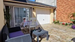 een patio met 2 stoelen en een tafel op een stenen patio bij LogeYou in Chartres-de-Bretagne