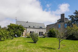 une ancienne maison en pierre avec une cour herbeuse dans l'établissement La Villa Bel Air, à Flamanville