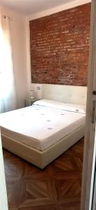łóżko w pokoju z ceglaną ścianą w obiekcie Il Melo Antico - appartamenti in villa d'epoca nel cuore del Monferrato w mieście Acqui Terme
