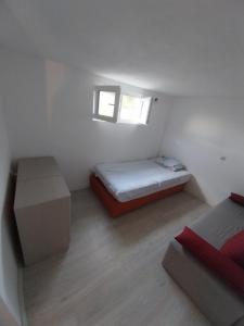 um pequeno quarto branco com uma cama e uma janela em Kaj Nana i Dedo em Skopje