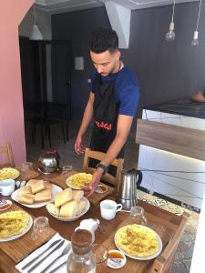 un hombre preparando comida en una mesa con platos de comida en Taza Organic Garden with view park and restaurant, en Taza