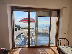 einen Balkon mit einem Tisch und einem Sonnenschirm in der Unterkunft Appartamento La Perla in San Nicola Arcella