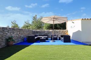 un patio con sillas y una sombrilla sobre una alfombra azul en La Resbalina de Arribes, en Trabanca