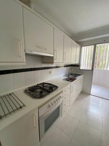 a kitchen with white cabinets and a stove top oven at A 50 metros del mar y en 2 paradas de bus estas en el centro de Alicante in Alicante