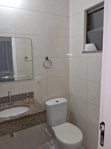 een badkamer met een toilet, een wastafel en een spiegel bij APTO LINDO FRENTE PRAIA GRANDE in Arraial do Cabo