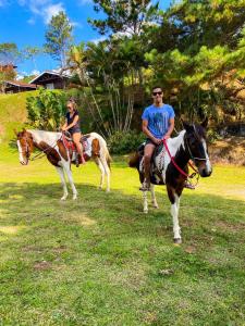 un hombre y una mujer montando caballos en un campo en Chalé Heliconia, en Juquitiba