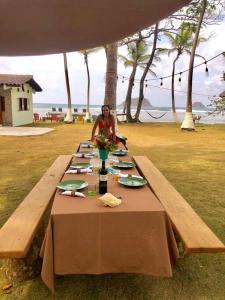 una mujer sentada en una mesa de picnic con una mesa en Puntita Manzanillo, fantastic sea and jungle retreat en La Guayra