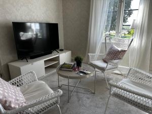 een woonkamer met een tv en stoelen en een tafel bij Quadambra Park in Gärsnäs