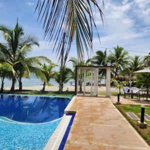 - un kiosque à côté d'une piscine bordée de palmiers dans l'établissement Costa Serena Casa 3, à Coveñas
