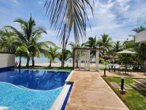 a pool at the beach with a gazebo and palm trees at Costa Serena Casa 3 in Coveñas