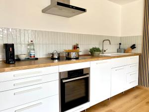a kitchen with white cabinets and a stove top oven at Top modernes Appartement mit Blick ins Grüne in Kißlegg