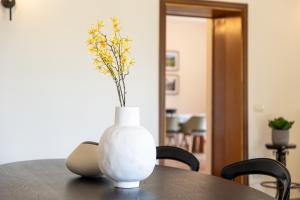 a white vase with flowers in it sitting on a table at Villa Degli Olivi is located in Saragano in Saragano