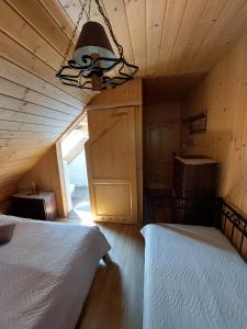 un dormitorio en el ático con 2 camas y una lámpara de araña en Bieszczadzkie Marzenie, en Wetlina