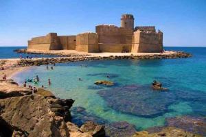 una playa con gente en el agua y un castillo en Casa Gialla - Bilocale indipendente, en Soverato Superiore