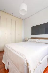 a white bedroom with a large white bed in it at Luminosa vivienda con garaje in Madrid