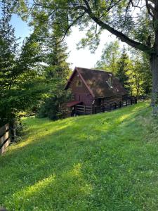 une grange sur une colline avec de l'herbe verte et des arbres dans l'établissement Domek na Polance, à Rajcza