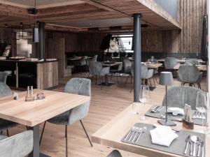 un ristorante con pavimenti e tavoli in legno e sedie di Belmonte Tirol - Boutique Hotel a Sillian