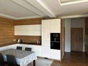 a kitchen with white cabinets and a table with chairs at Sea Resort 1 & Spa in Władysławowo