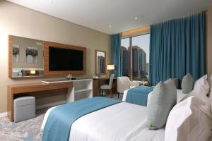 a hotel room with two beds and a desk and a television at Cantonal Hotel by Warwick in Riyadh +85 photos