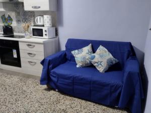um sofá azul com duas almofadas na cozinha em Bilocale per vacanze a Vada em Vada