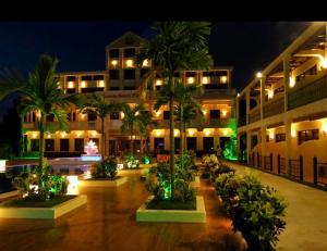 a building with palm trees in a courtyard at night at Victoria Beach Hotel in Toamasina