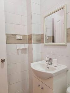 a white bathroom with a sink and a mirror at Exclusivo Dpto 101 con Terraza en Antofagasta in Antofagasta