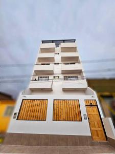 een hoog wit gebouw met bruine deuren en ramen bij Exclusivo Dpto 101 con Terraza en Antofagasta in Antofagasta