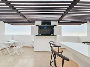 Habitación con mesas y sillas blancas y TV. en Exclusivo Dpto 101 con Terraza en Antofagasta, en Antofagasta