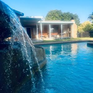 a swimming pool with a fountain in front of a house at Kuhle's Guest House in Richards Bay