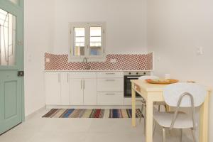 a kitchen with white cabinets and a table and chairs at Mirtilo in Kardamena Centre in Kardamaina