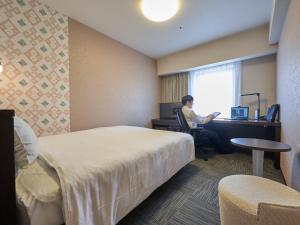 mężczyzna siedzący przy biurku w pokoju hotelowym w obiekcie Richmond Hotel Aomori w mieście Aomori