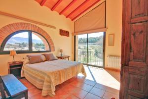 een slaapkamer met een bed en een groot raam bij Mas Del Cigarrer Allotjament Rural in Horta de San Joan