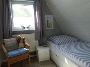 ein Schlafzimmer mit einem Bett, einem Stuhl und einem Fenster in der Unterkunft Ferienhaus-Slanitz in Harlesiel