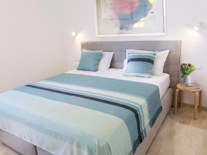 Bett mit blauer und weißer Bettwäsche und Kissen in der Unterkunft Modern Apartment for 4 persons, Sea view, near the beach, Parking in Supetar