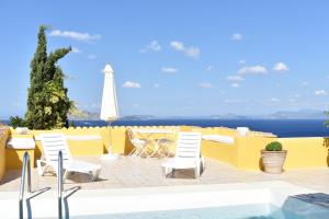 une terrasse avec une table et des chaises et l'océan dans l'établissement Chez Le Goff, à Hydra