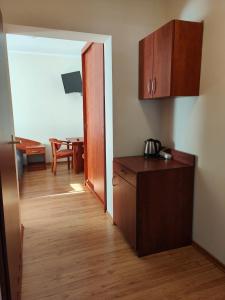 a kitchen with a wooden floor and a room with a table at Pensjonat Lubar in Dziwnów