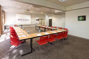 une salle de conférence avec une grande table et des chaises rouges dans l'établissement Mercure Strasbourg Aéroport, à Ostwald