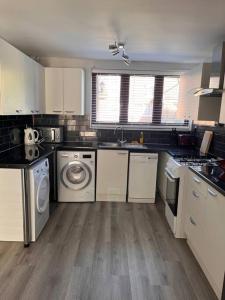 a kitchen with a washing machine and a washer and dryer at Spacious and comfy in Woolwich